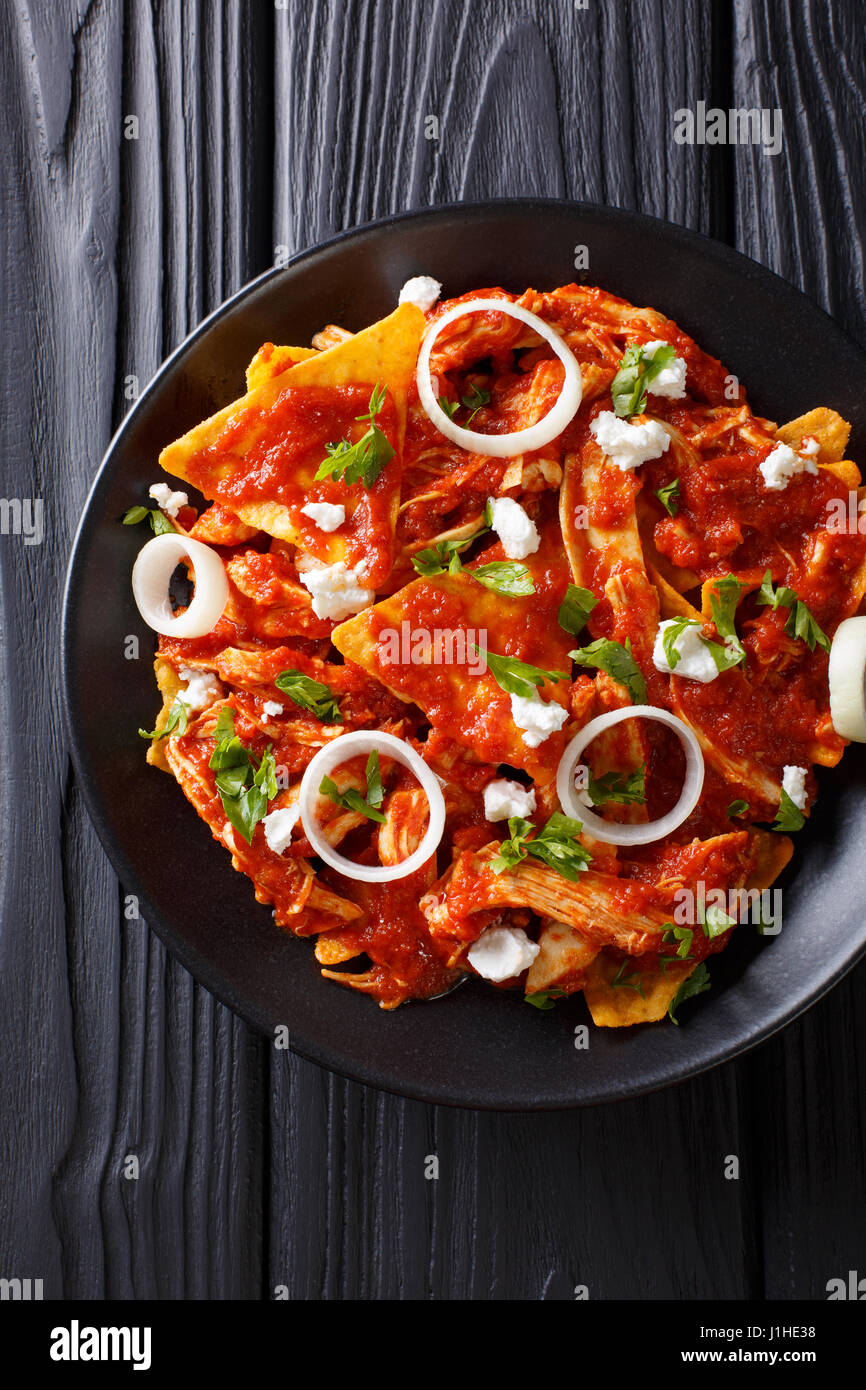 Hot Mexican food chilaquiles with chicken close-up on a plate on the table. Vertical view from above Stock Photo