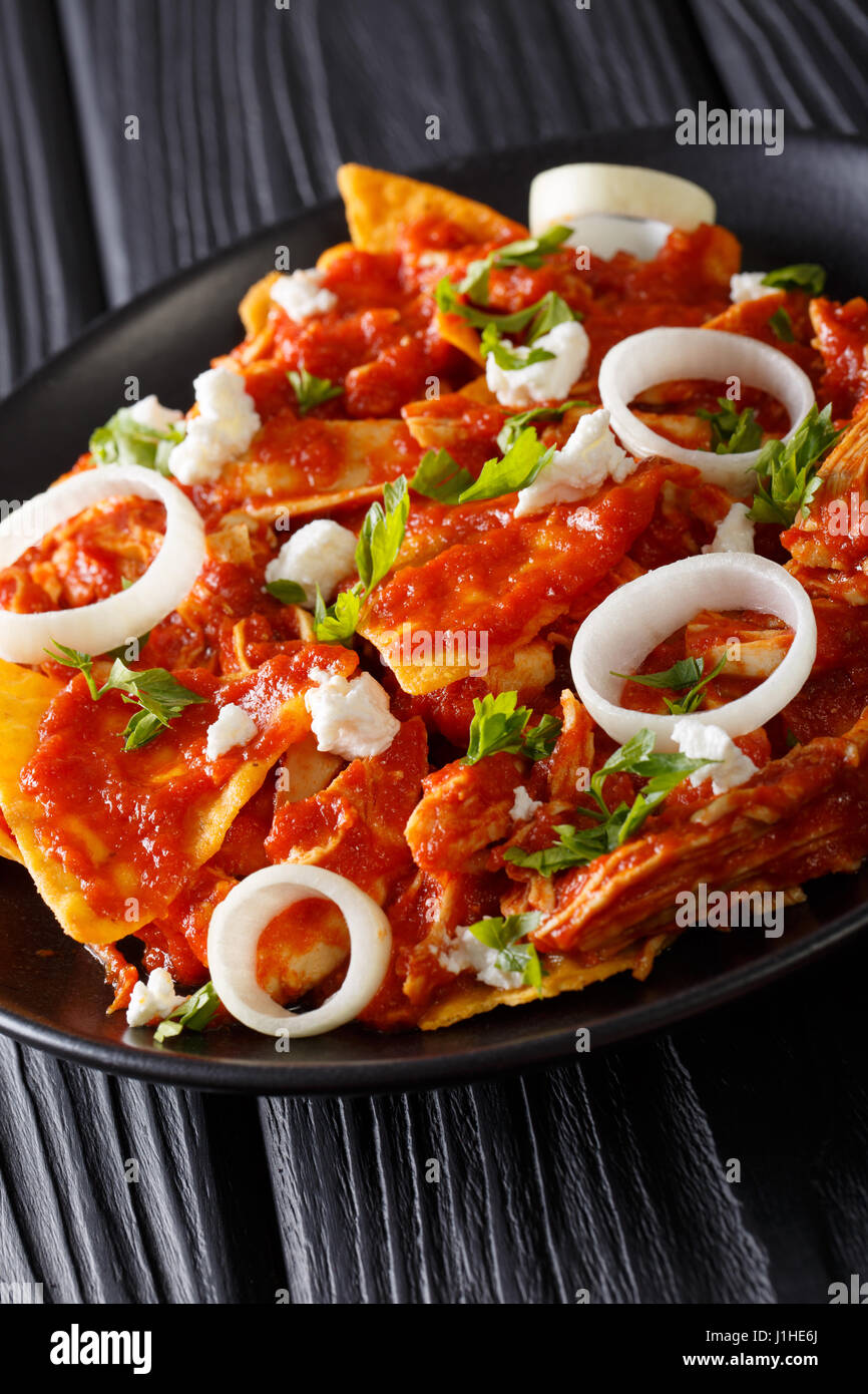 Mexican chilaquiles with chicken closeup on a plate on a table. vertical Stock Photo