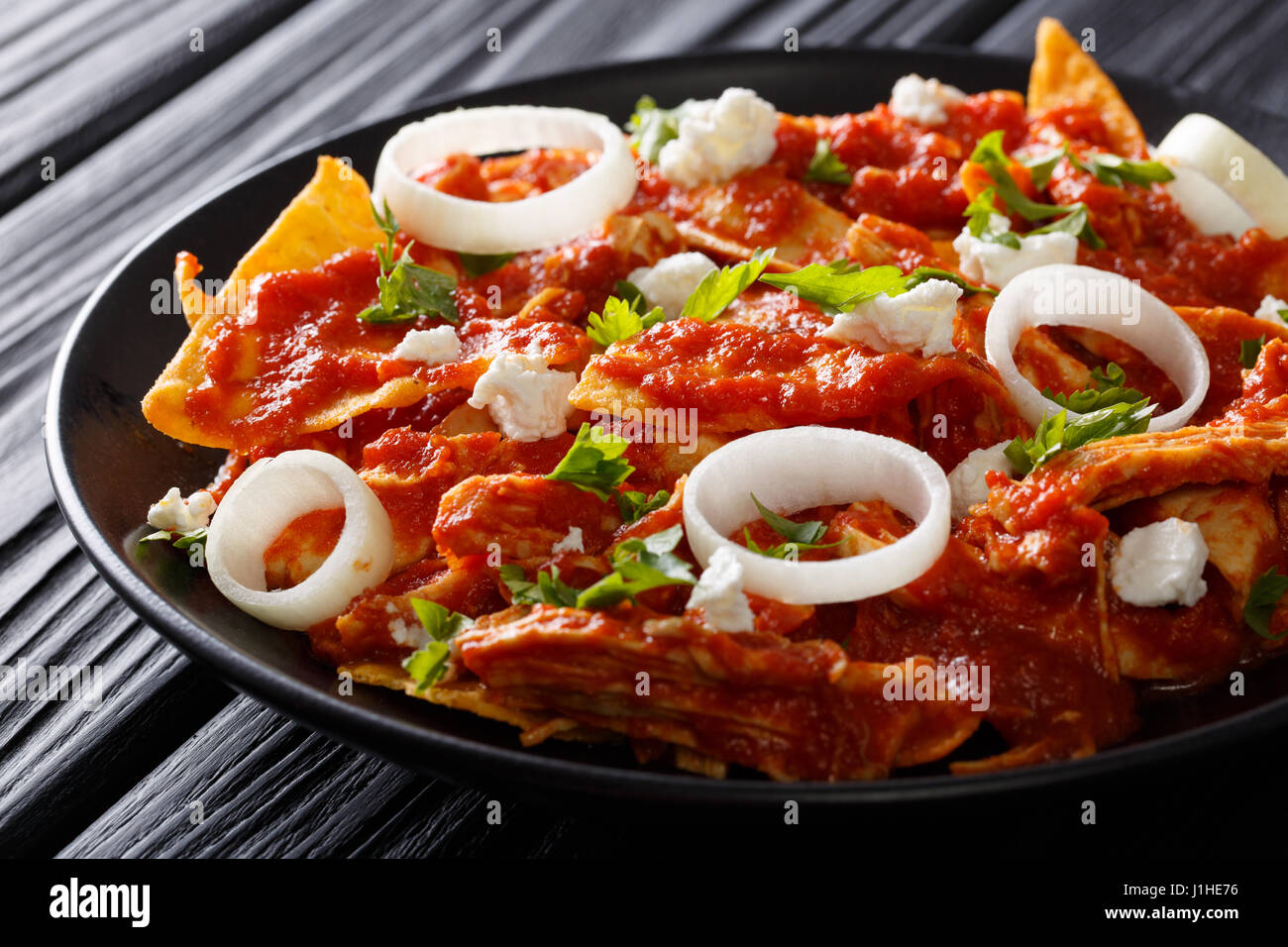 chilaquiles Mexican nachos with tomato salsa, chicken and cheese close-up on a plate. horizontal Stock Photo
