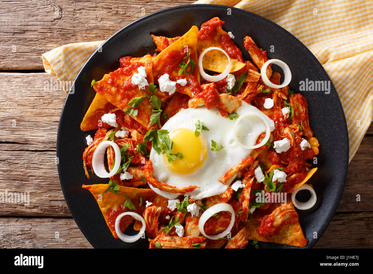 Mexican breakfast: chilaquiles with egg and chicken close-up on a plate. Horizontal view from above Stock Photo