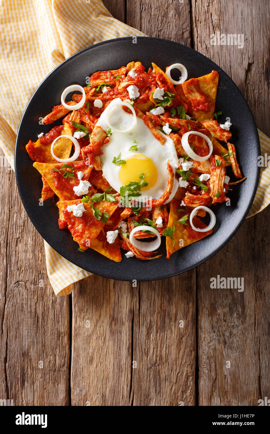 Mexican nachos with tomato salsa, chicken and egg close-up on a plate. Vertical view from above Stock Photo
