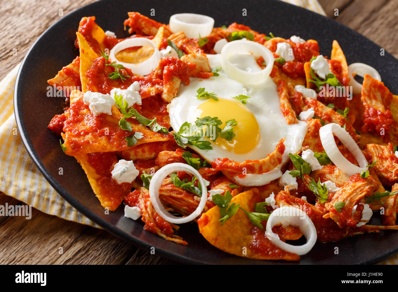Mexican chilaquiles with fried egg and chicken close-up on a plate. horizontal Stock Photo