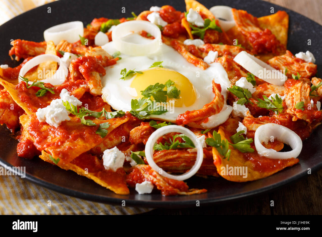 Mexican breakfast: chilaquiles with egg and chicken close-up on a plate. horizontal Stock Photo
