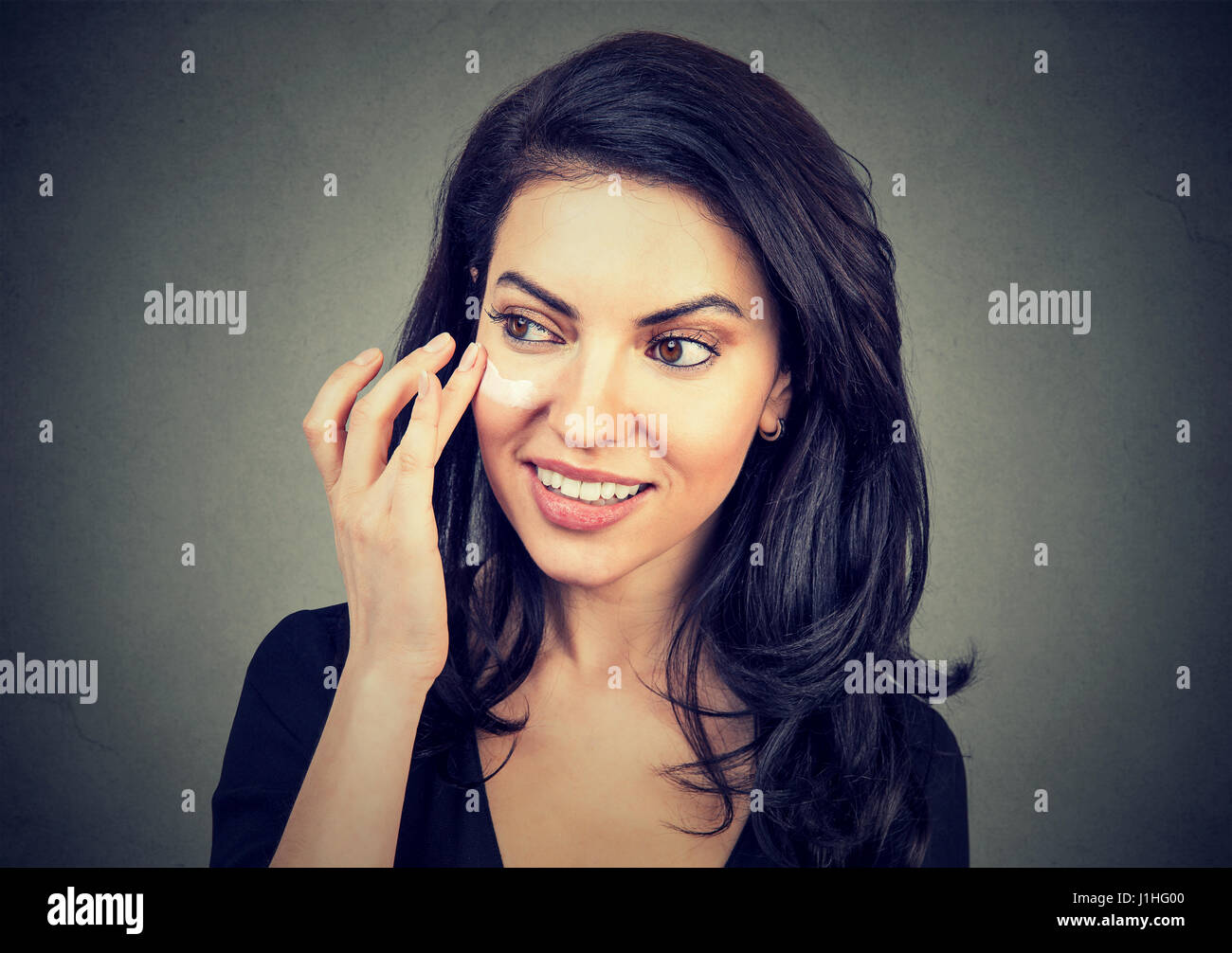 Attractive woman applying makeup cream Stock Photo