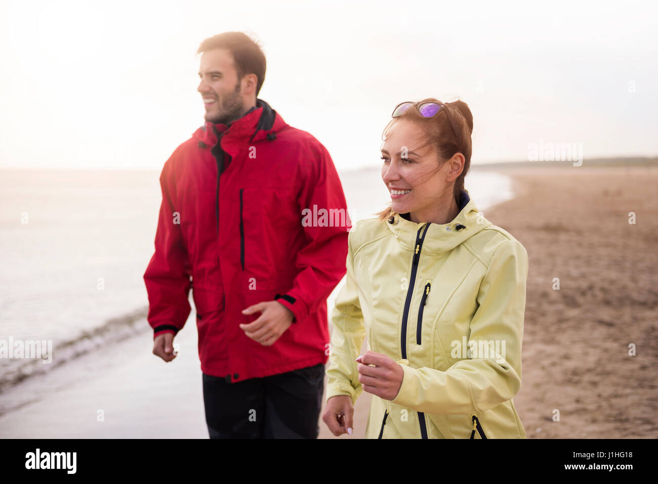 Couple jogging on the beach in cold weather Stock Photo