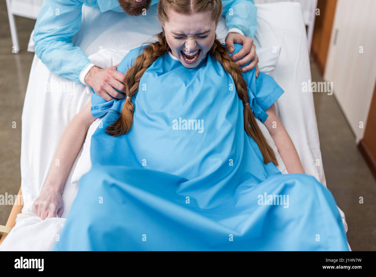 pregnant woman giving birth in hospital while man hugging her Stock Photo