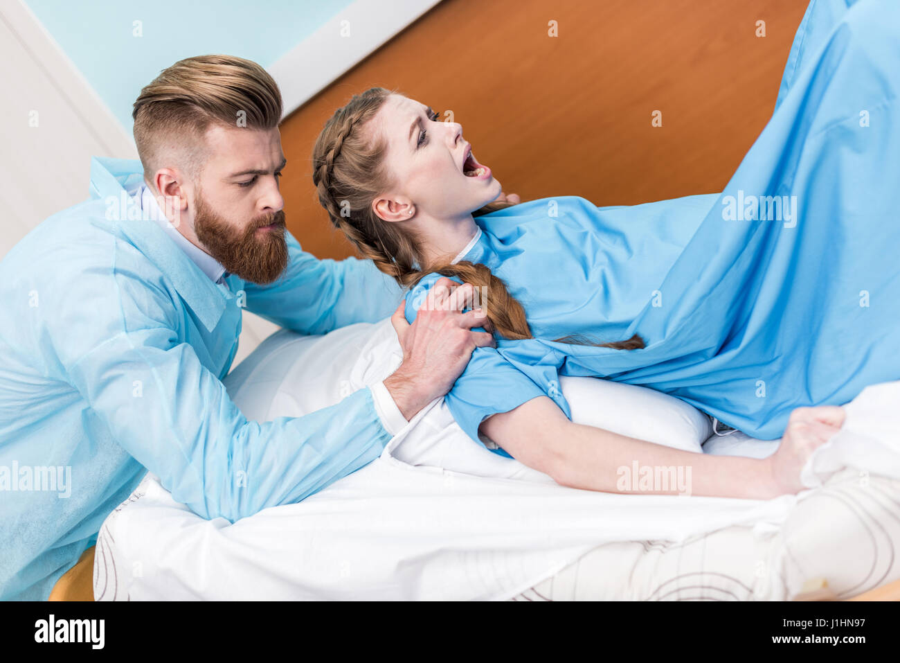 pregnant woman giving birth in hospital while man hugging her Stock Photo