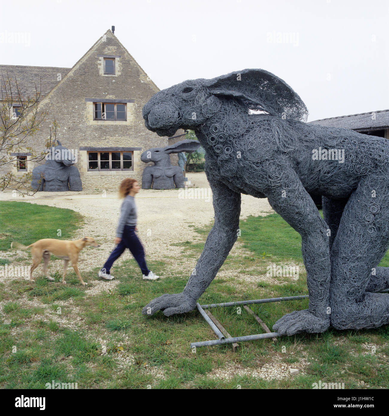 Woman walking by rabbit-human hybrid sculptures. Stock Photo
