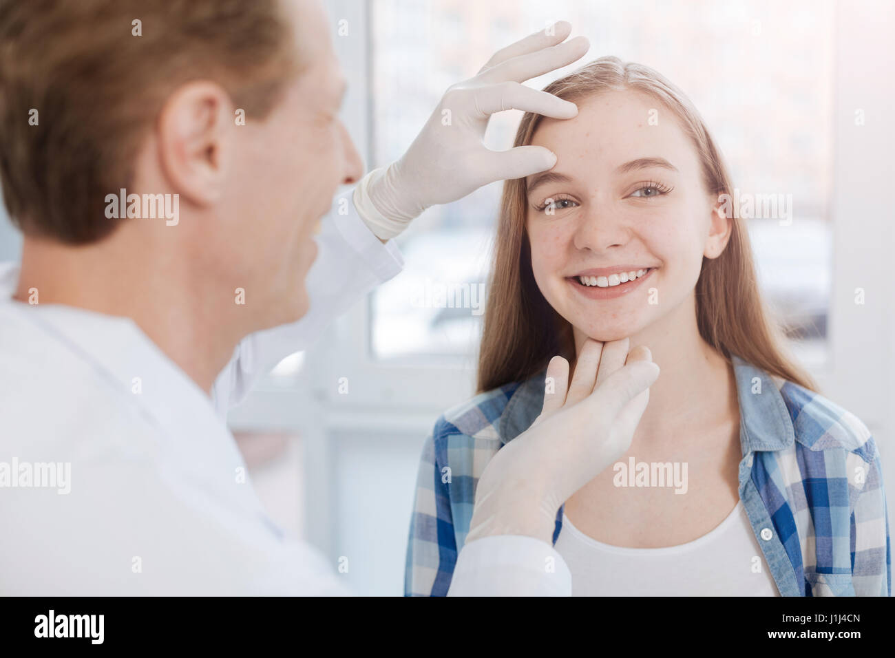 Delighted dermatologist examining patient skin in the hospital Stock Photo
