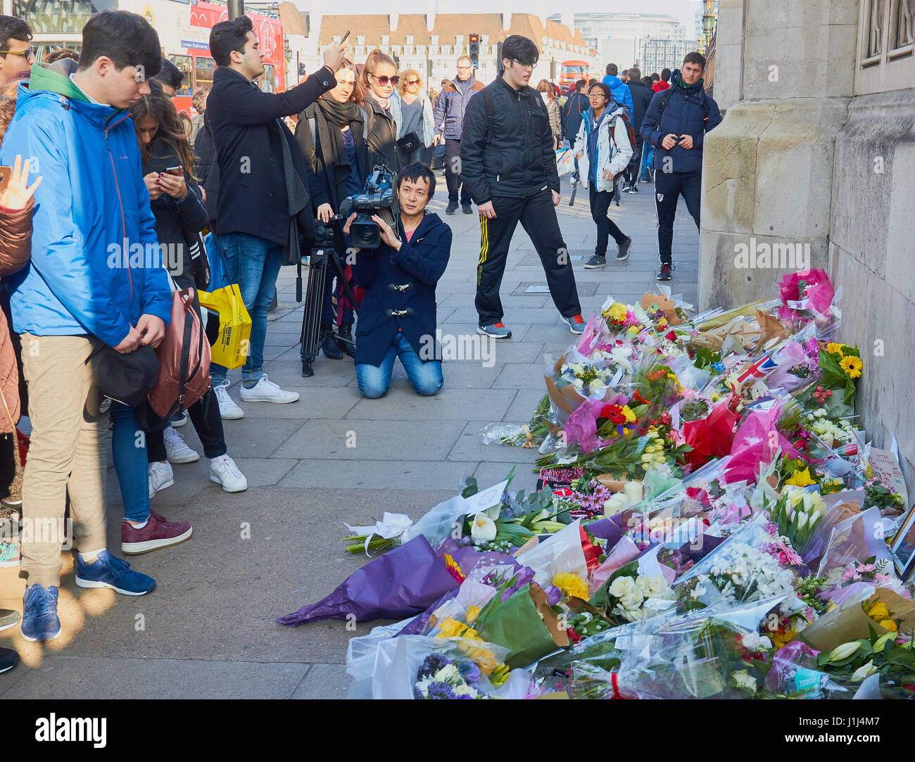 Tourists and a cameraman looking at flowers and tributes to victims of the Westminster terrorist attack, London, England Stock Photo