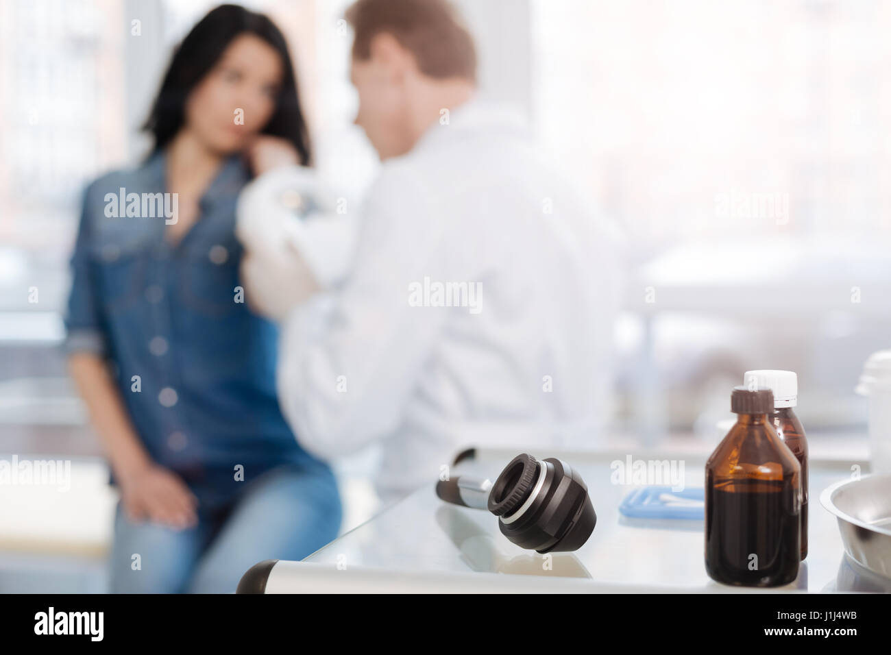 Skillful doctor using medical instruments for skin examination indoors ...