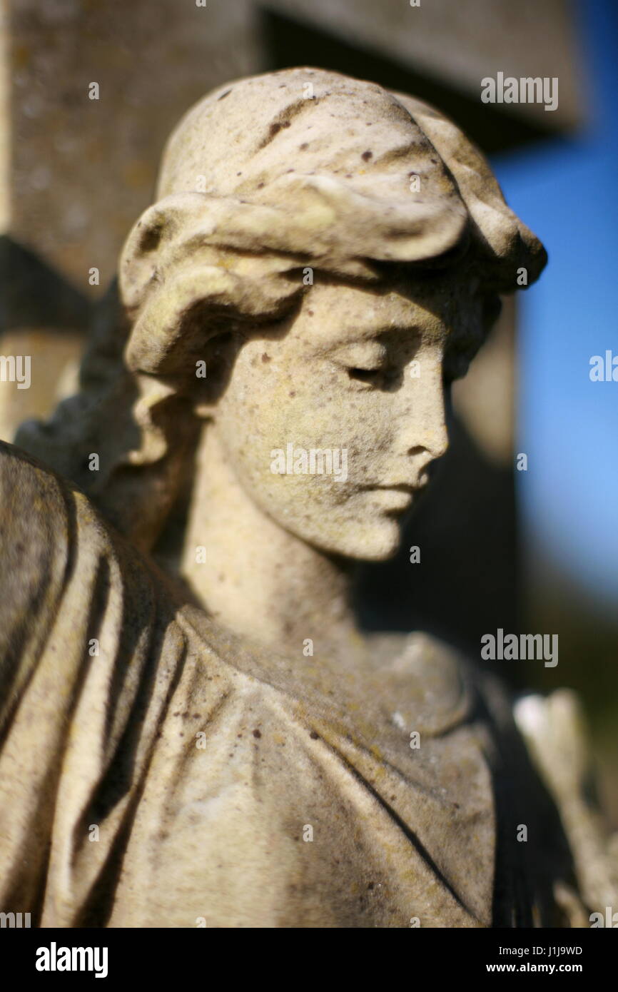 A figure of an angel on a cross in a cemetery Stock Photo