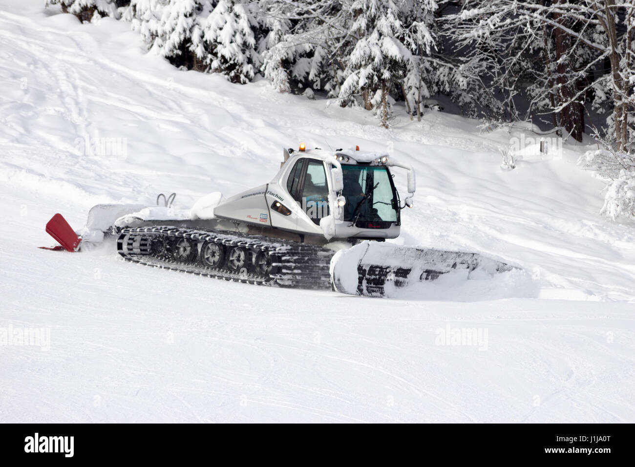 FLACHAU, AUSTRIA - JAN 7, 2012: Snow groomer on a ski piste in the Austrian Alps. These pistes are part of the Ski Armad network, the largest of Europ Stock Photo