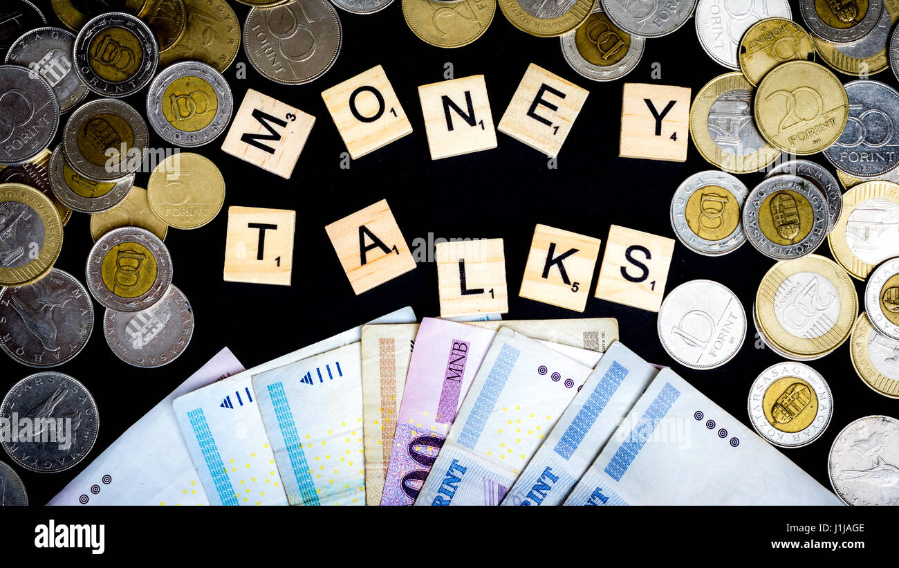 Budapest. Hungary, 21st of April 2017 - Scrabble pieces and money - coins and paper- in front of black background Stock Photo