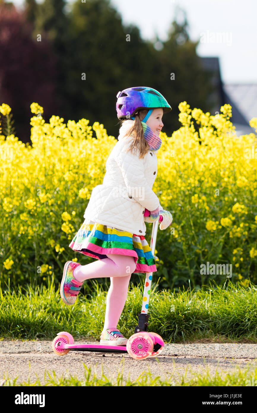 Child riding scooter on way back to school. Little girl playing
