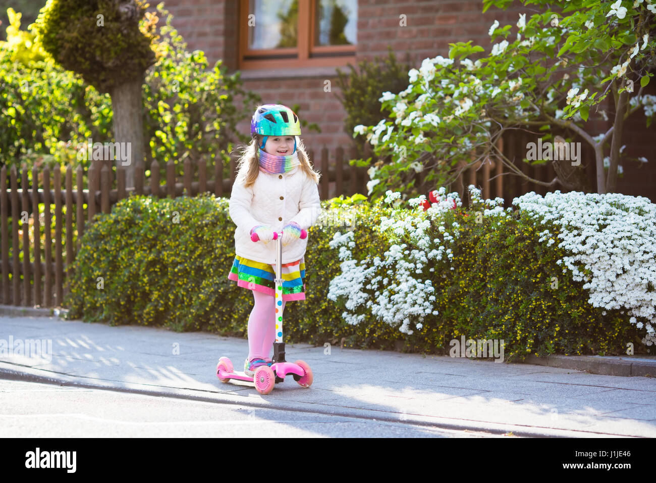 Child riding scooter on way back to school. Little girl playing