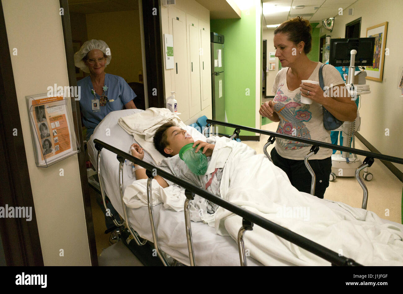 Mom comforts son as nurse wheels bed to room from appendicitis surgery. St Paul Minnesota MN USA Stock Photo