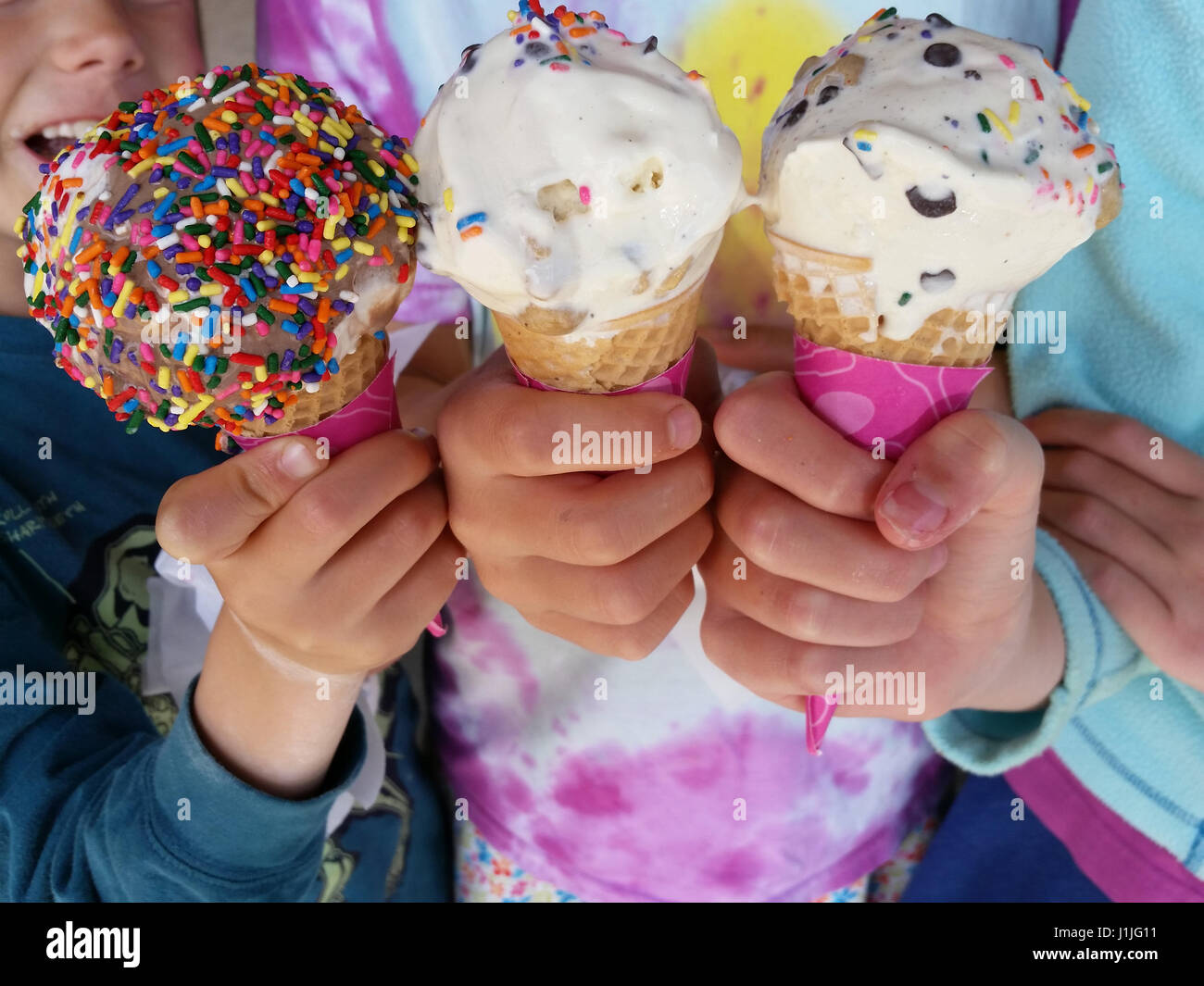 Close up of three ice cream cones held by three children to celebrate the start of summer or end of school year. Stock Photo