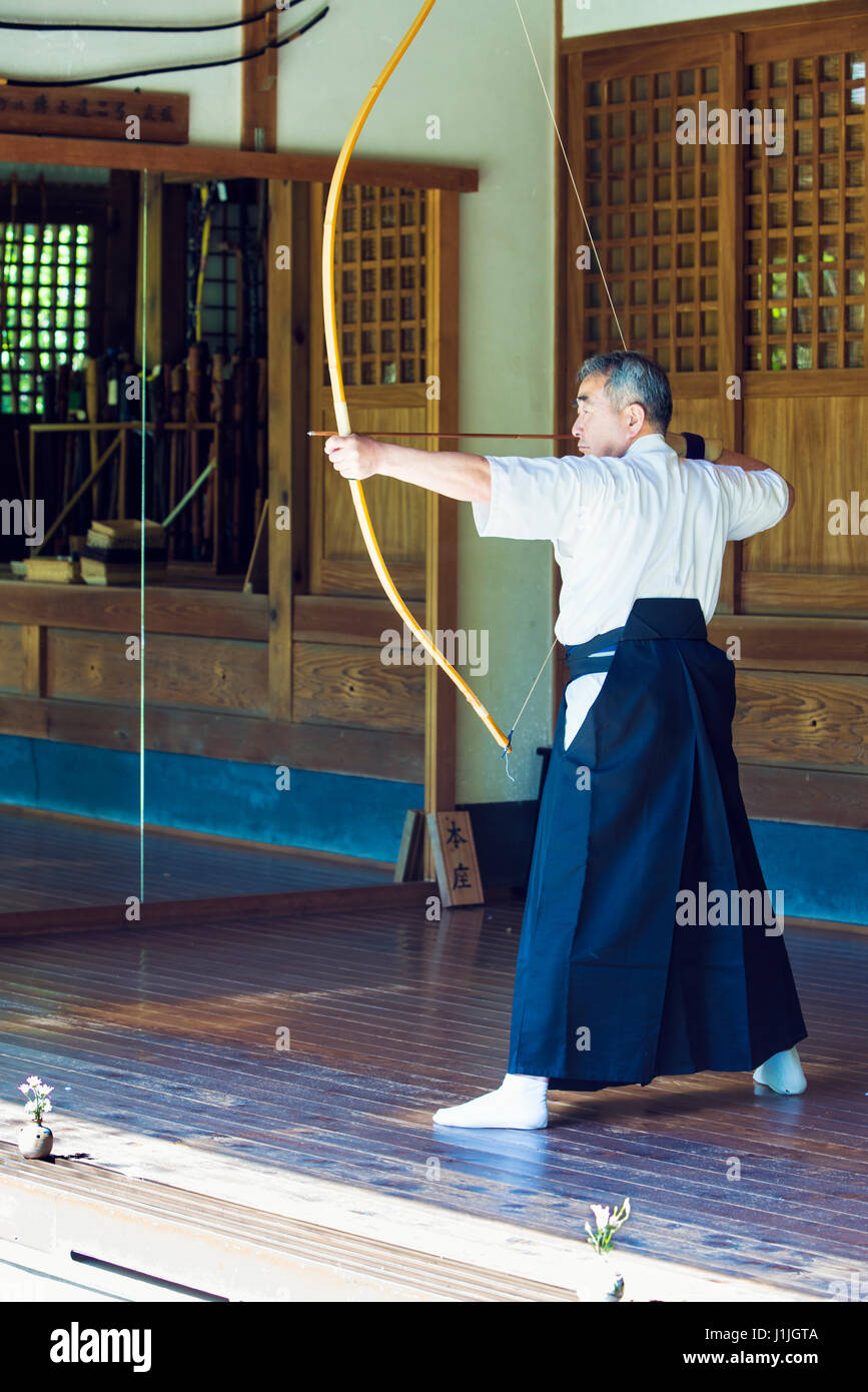 A Japanese archer, kyudoka, practicing kyudo in a traditional dojo in Kamakura, Japan Stock Photo