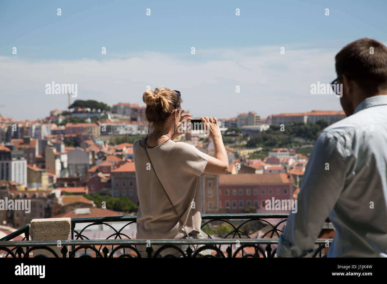 A lady taking a photograph of the city of Lisbon from a viewing terrace at the Barrio Alto in Portugal. Stock Photo