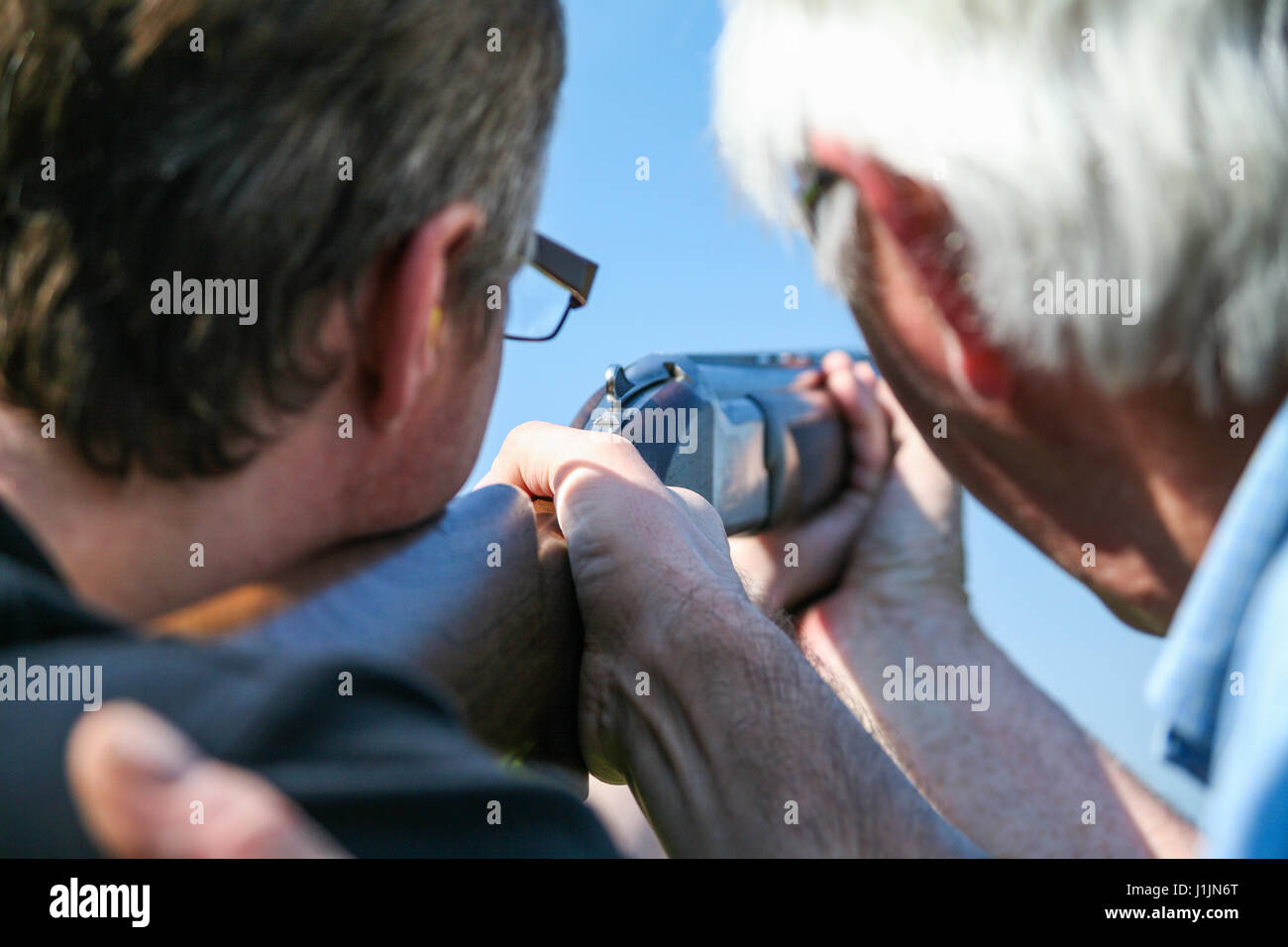One man coaches another at clay pigeon shooting range Stock Photo