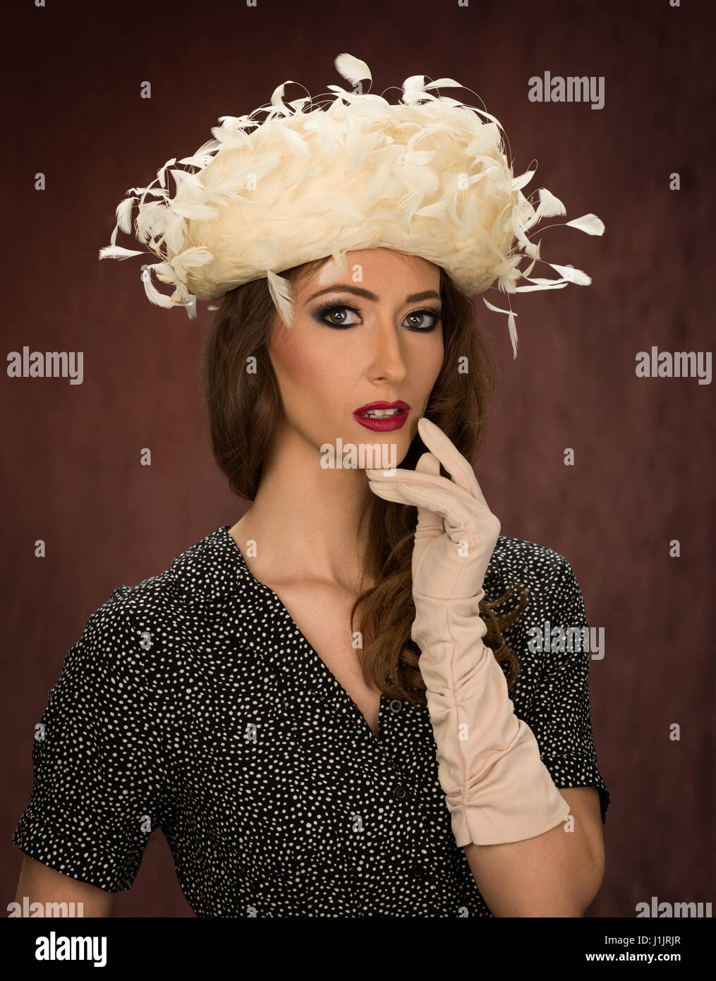 Young brunette model in a vintage white feathered hat Stock Photo