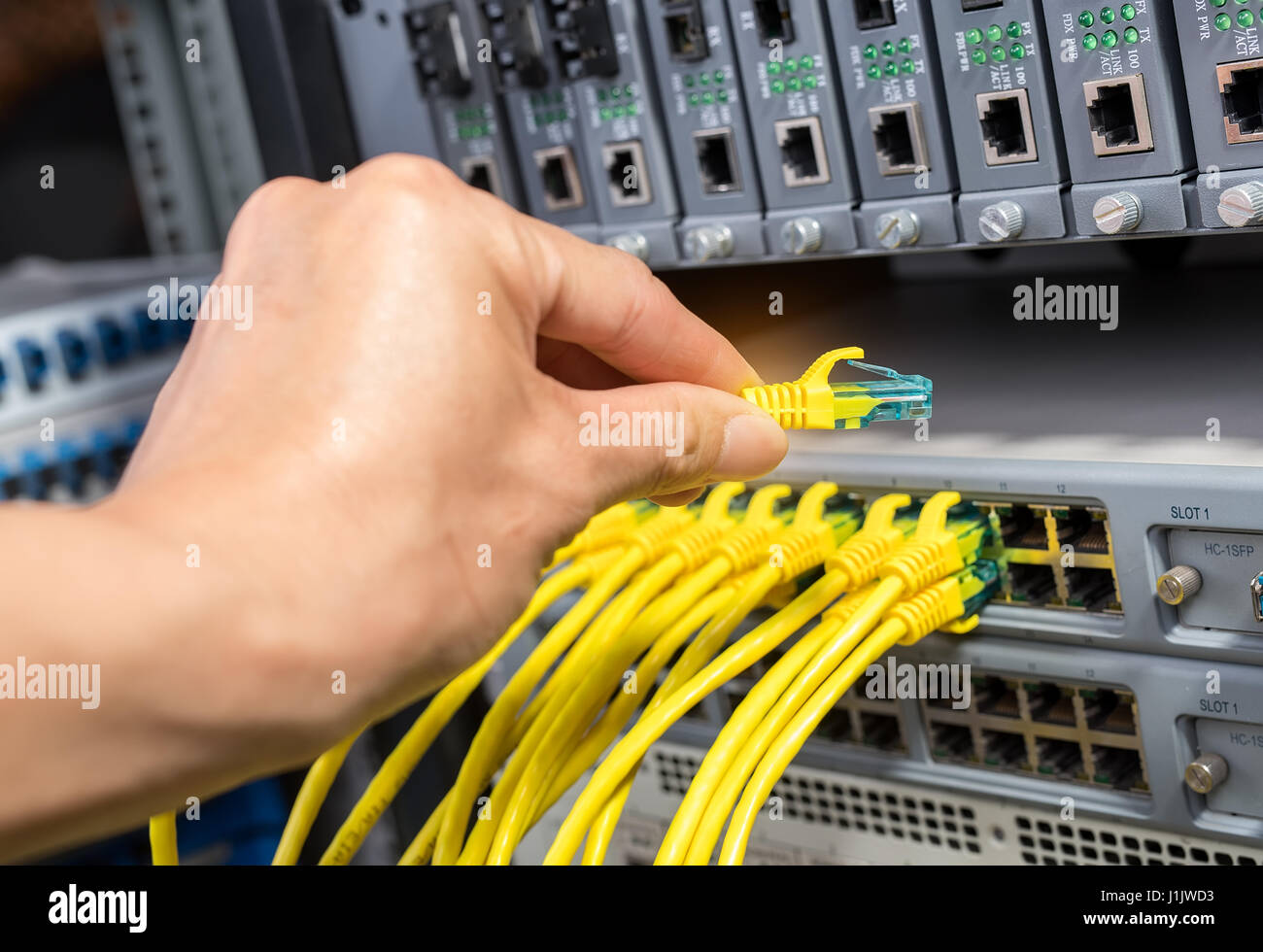 hand with network cables connected to servers in a datacenter Stock Photo