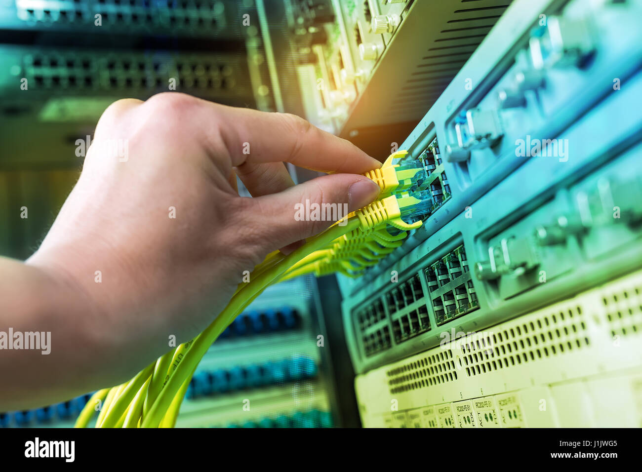 hand of administrator holding network cables connected to servers Stock Photo