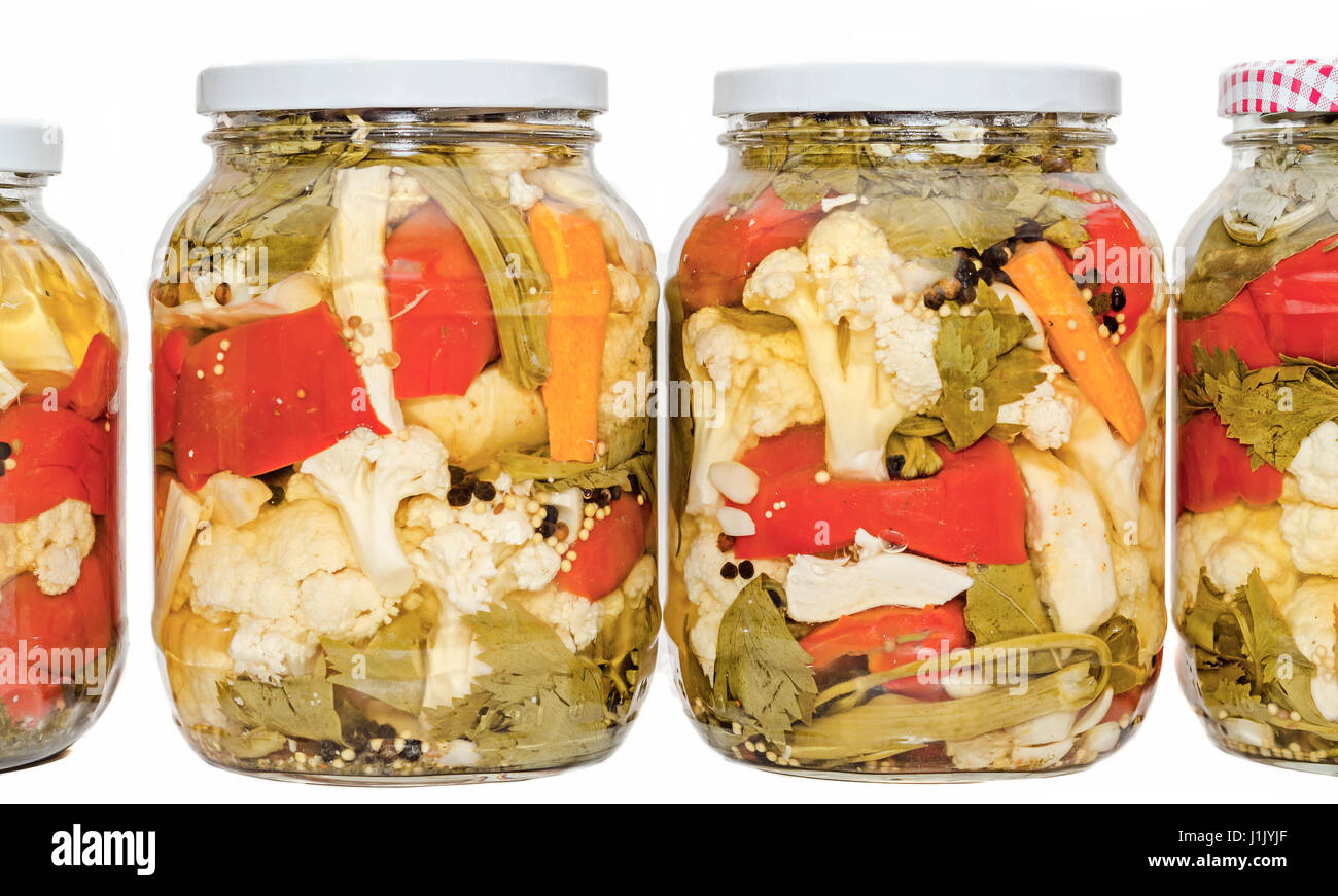 Jars with pickles containing cauliflower, cucumber, red pepper, onions