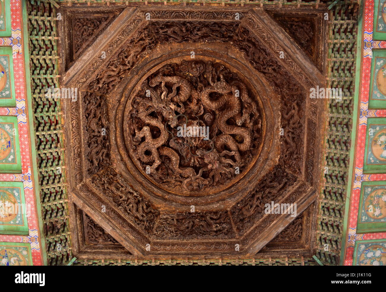 Wood carved Chinese dragons decorating the ceiling of a gazebo in the gardens of the Forbidden City in Beijing, China Stock Photo