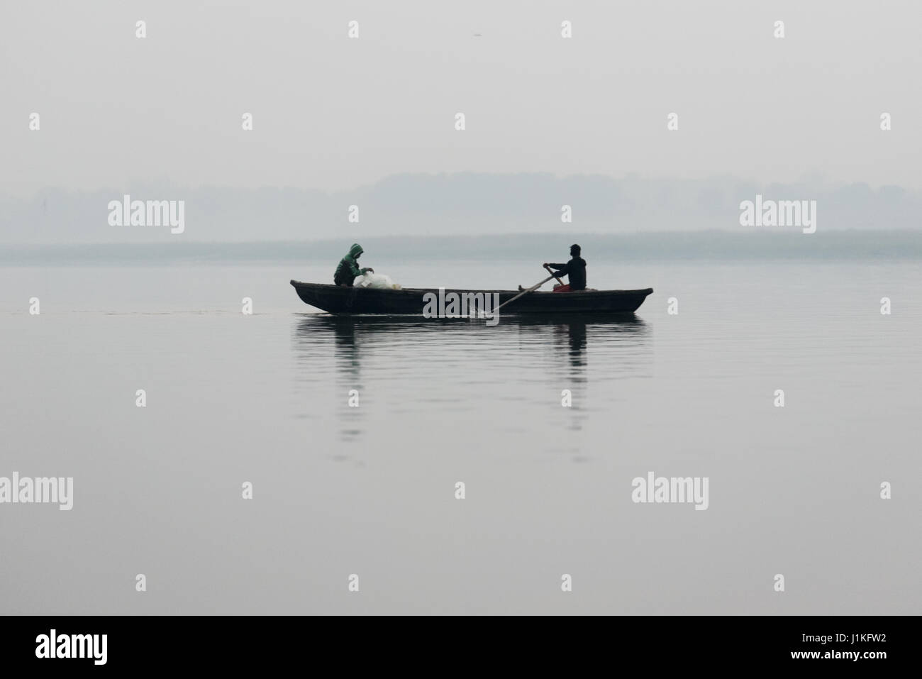 Two men rowing a boat on the river Ganges, Varanasi, India Stock Photo