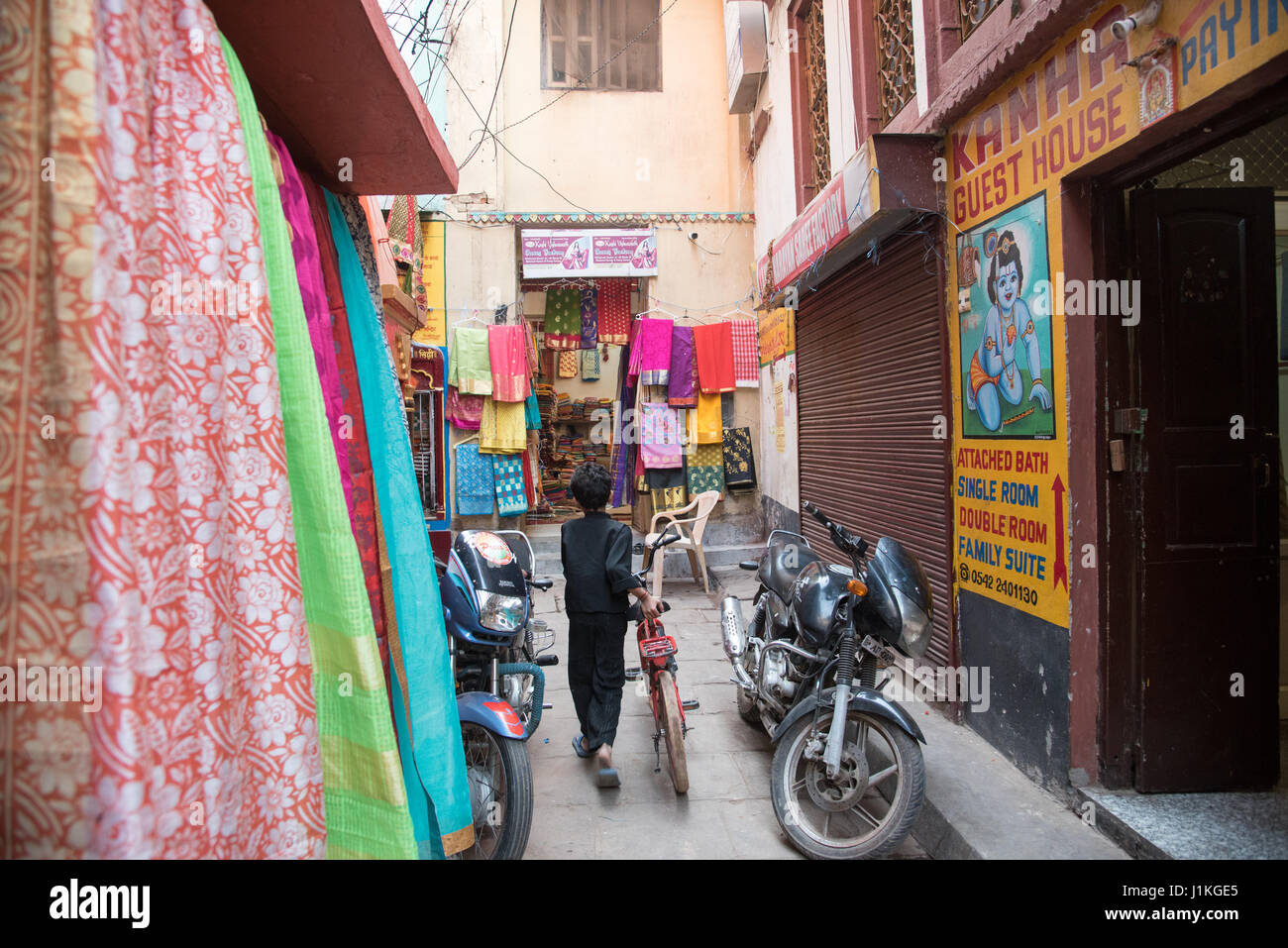 Boy pushing his bike through a narrow alley in Varanasi, India Stock Photo