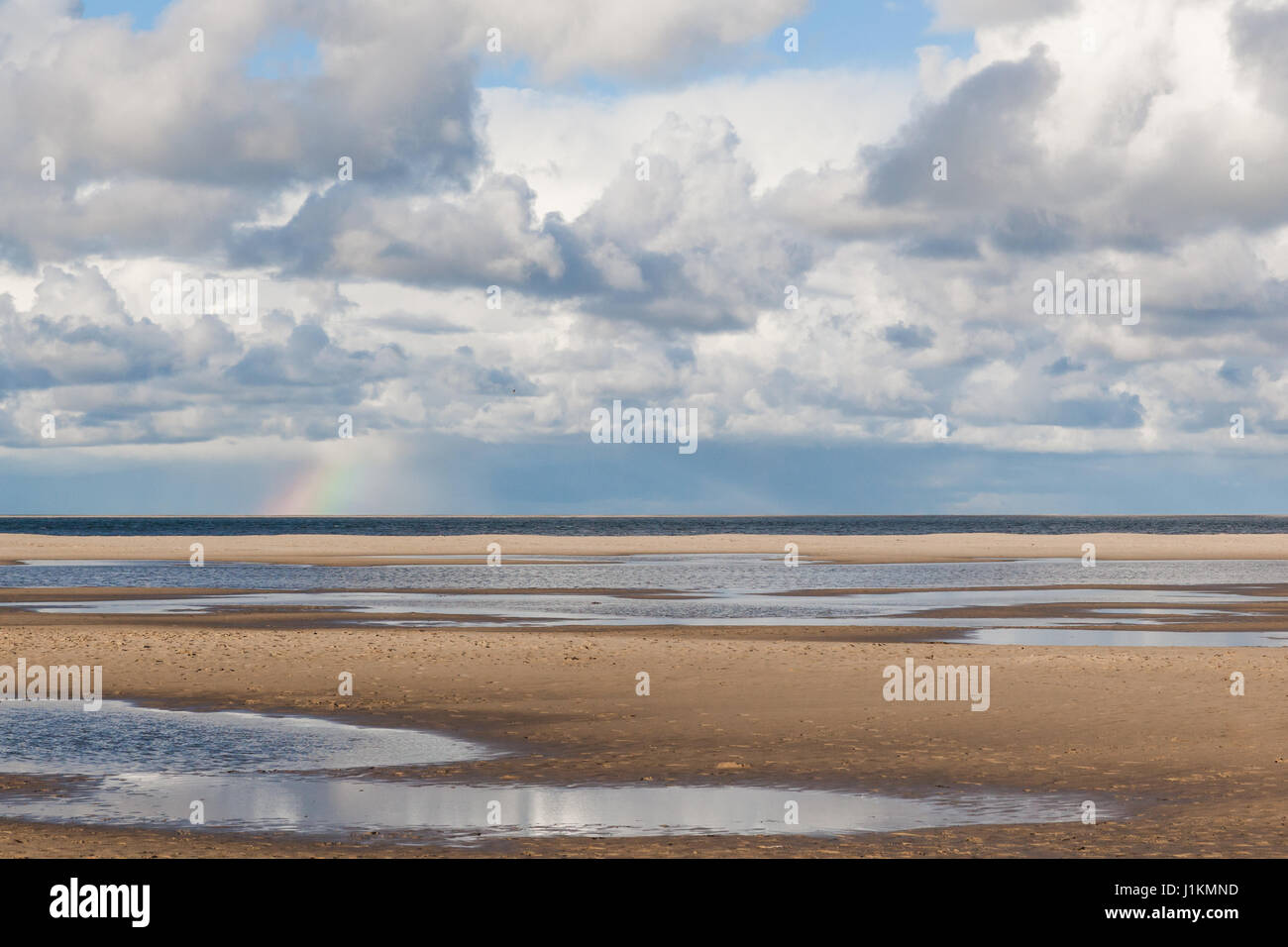 sea and sand with clouds and a rainbow on Texel, Wadden Island of the Netherlands Stock Photo