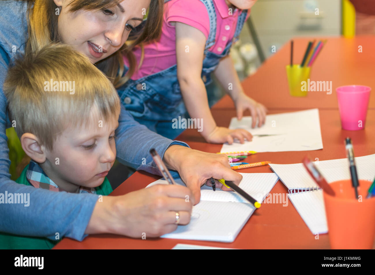Teacher coloring with children in the kindergarten Stock Photo