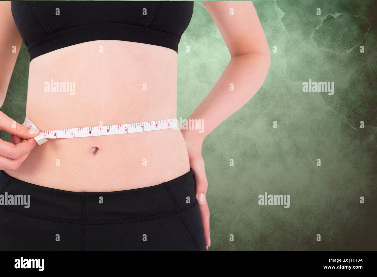 Digital composite of Midsection of woman measuring waist against green ...