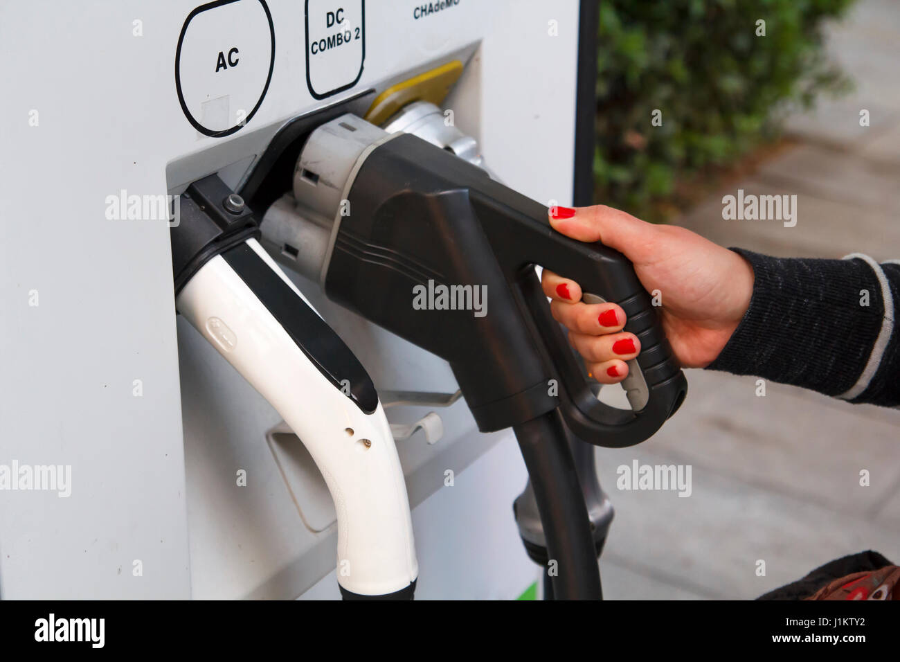Woman hands holding an electric socket for car battery recharge Stock