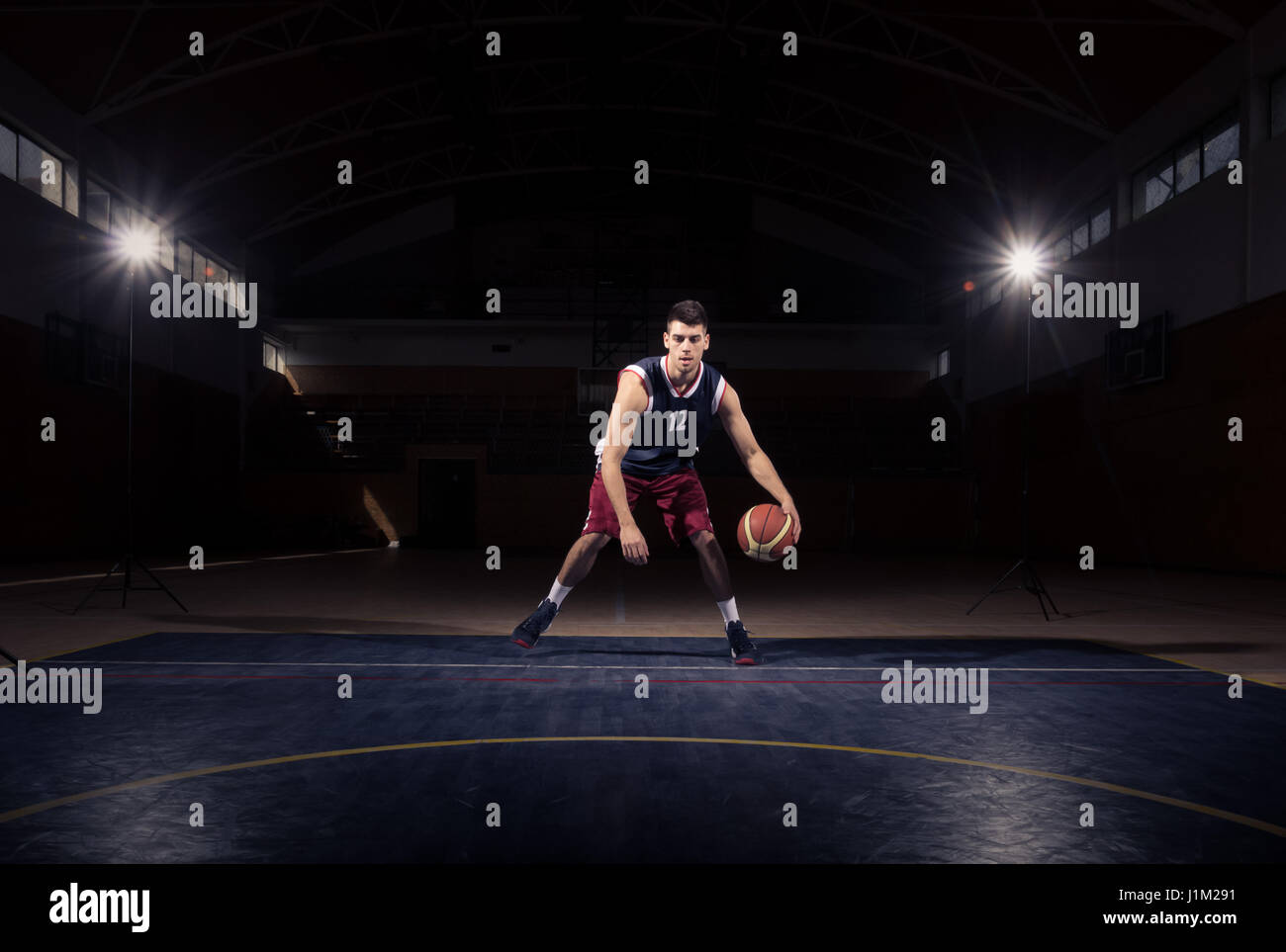 one young adult man, basketball player dribble ball, dark indoors basketball court Stock Photo
