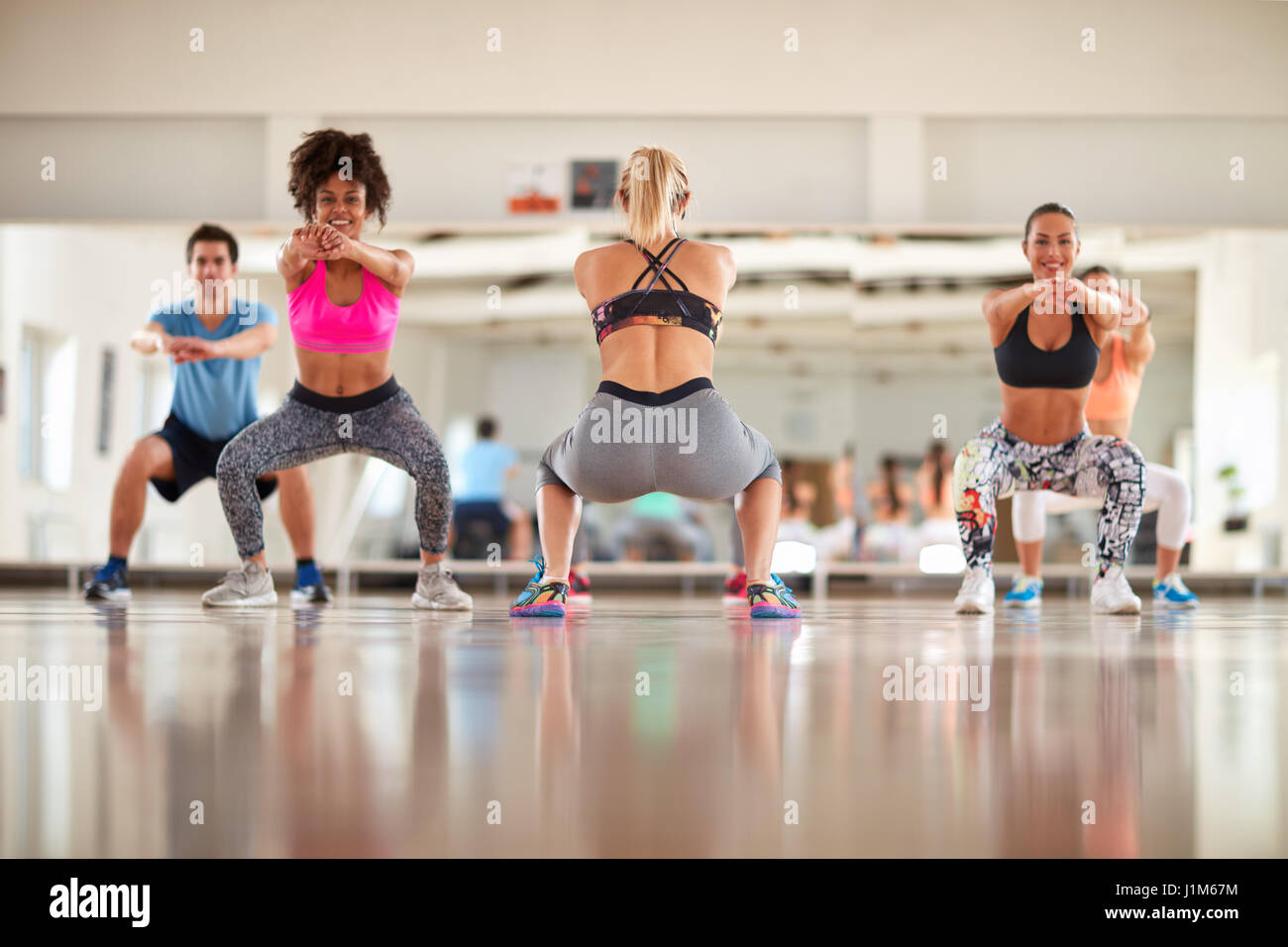 Fitness group warming up in gym with female instructor Stock Photo
