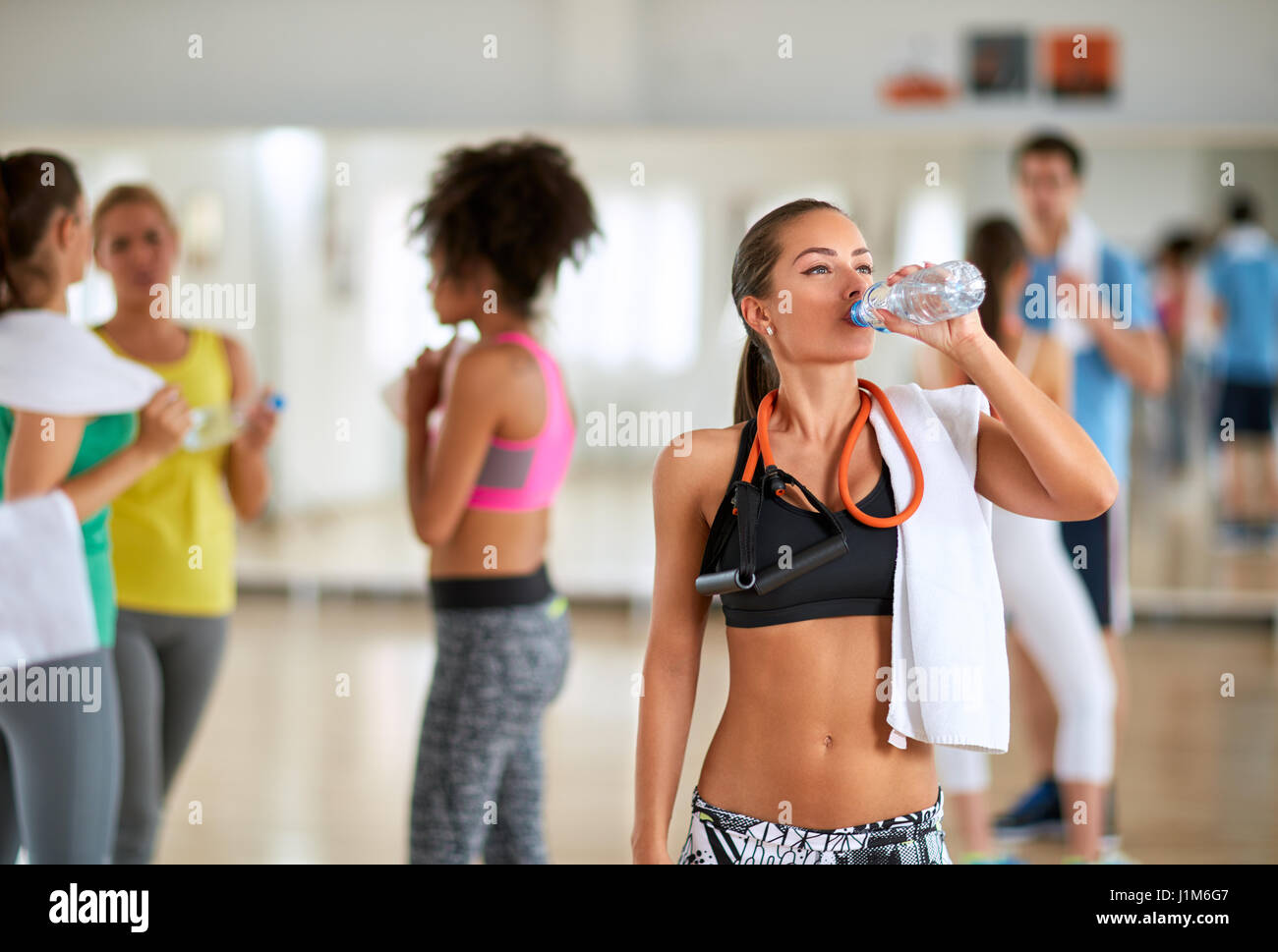 Young brunette drinking water in fitness class after training Stock Photo