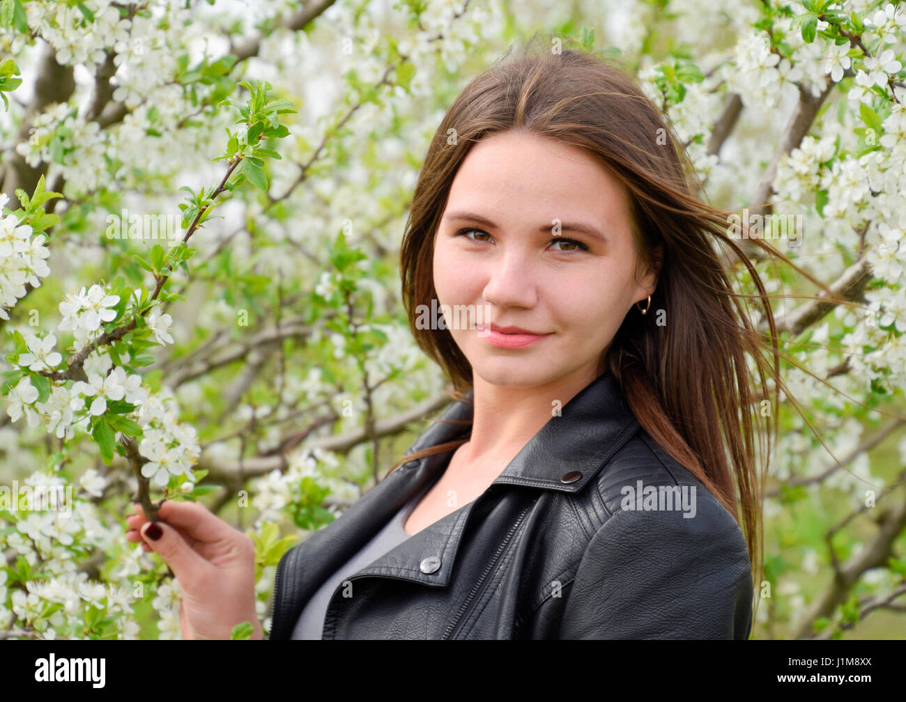 Beautiful fairy young girl in a flowering plum garden. Portrait of a
