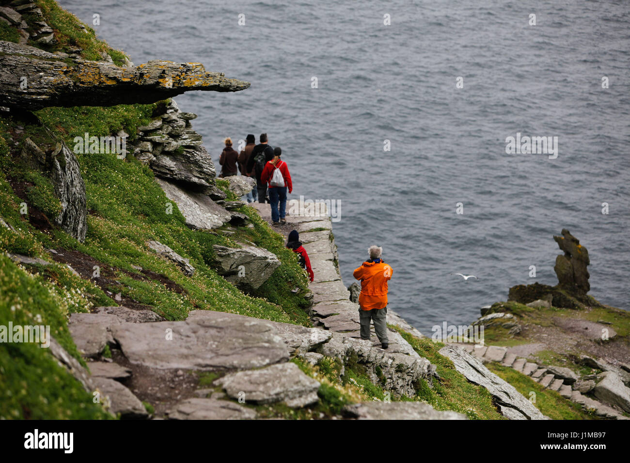 Walking the pathway on Skellig Michael with a sheer drop down to the sea. Stock Photo