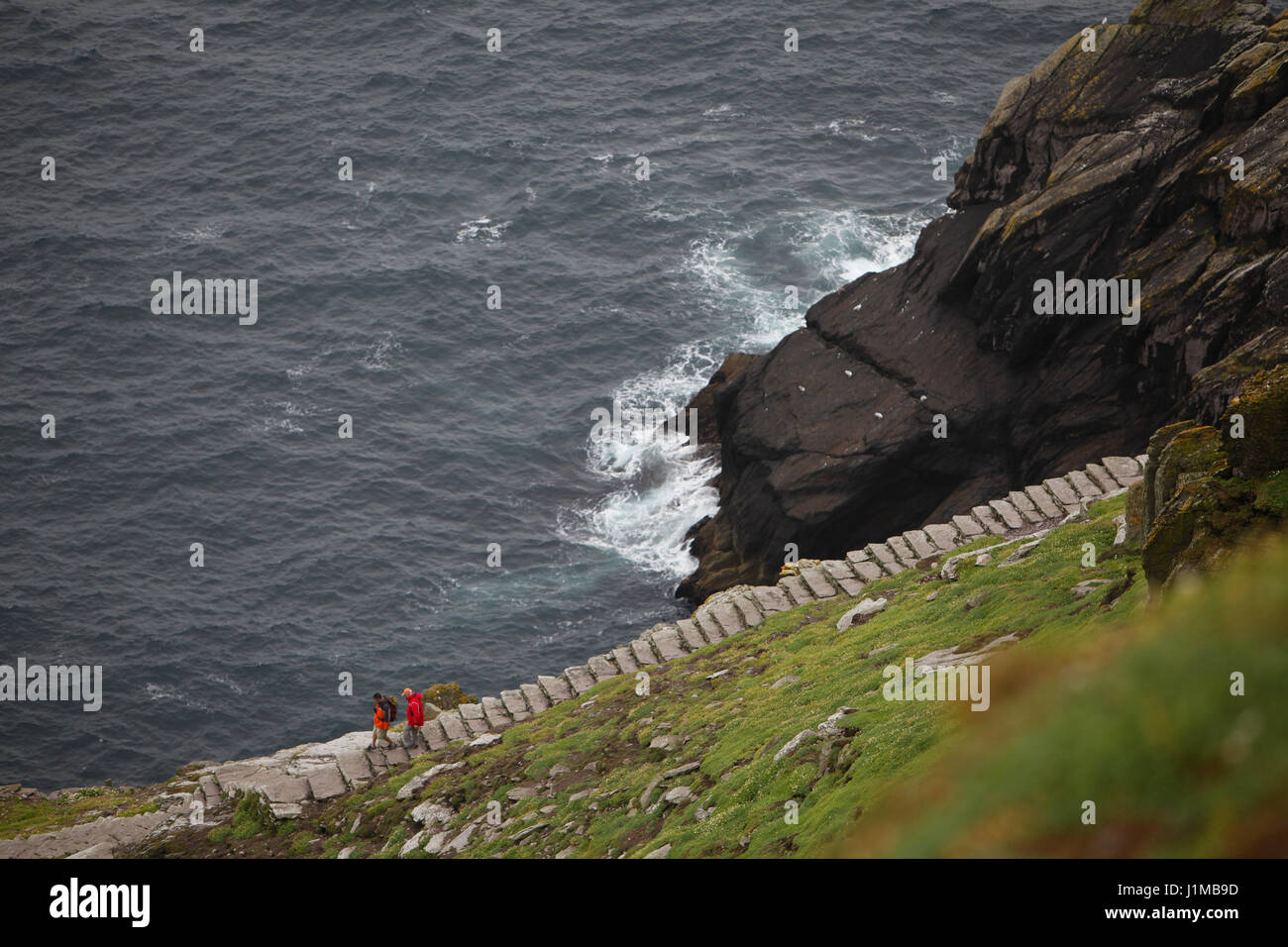 Walking the pathway on Skellig Michael with a sheer drop down to the sea. Stock Photo