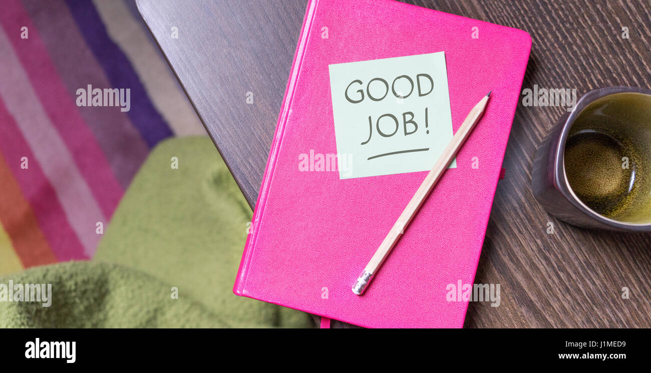 Pink notebook, pen and note with the text Good Job Stock Photo