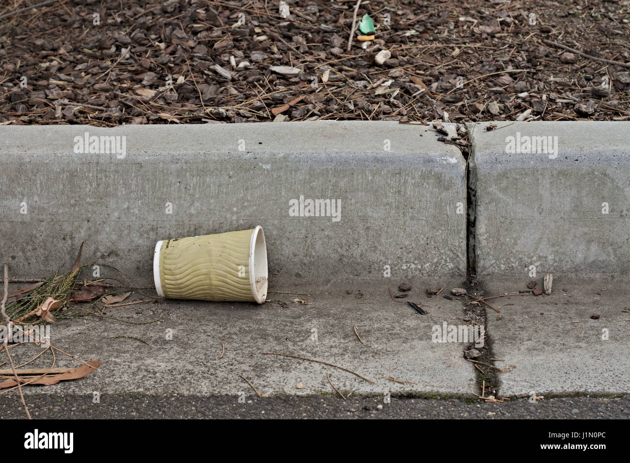 Takeaway coffee cup thrown away in the gutter as trash. Stock Photo