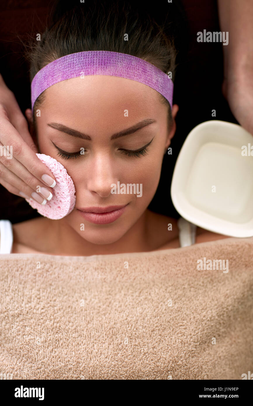 Skin treatment, beautician cleaning face of young female in spa salon Stock Photo