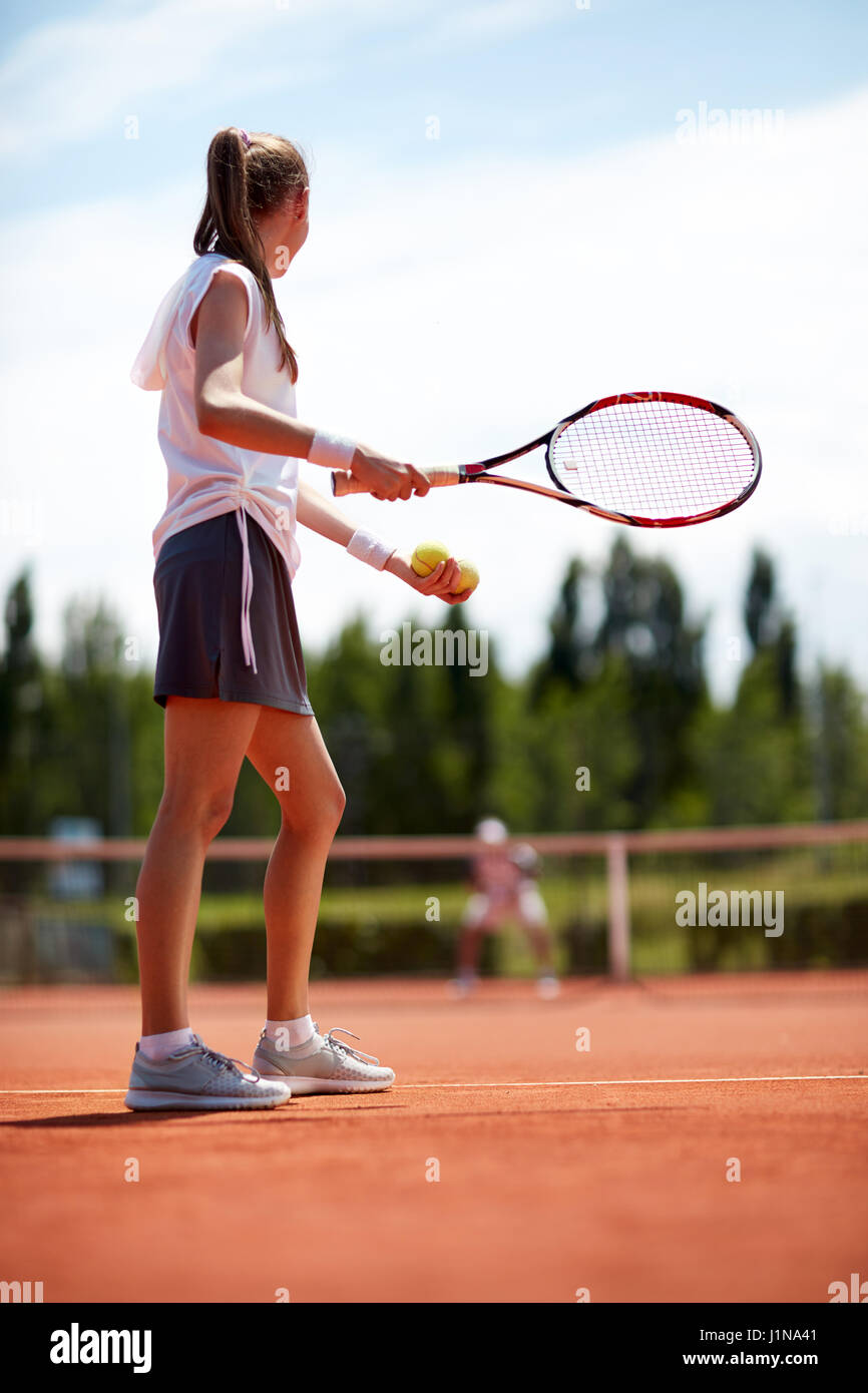 Female tennis player serving ball on tennis court, aside Stock Photo