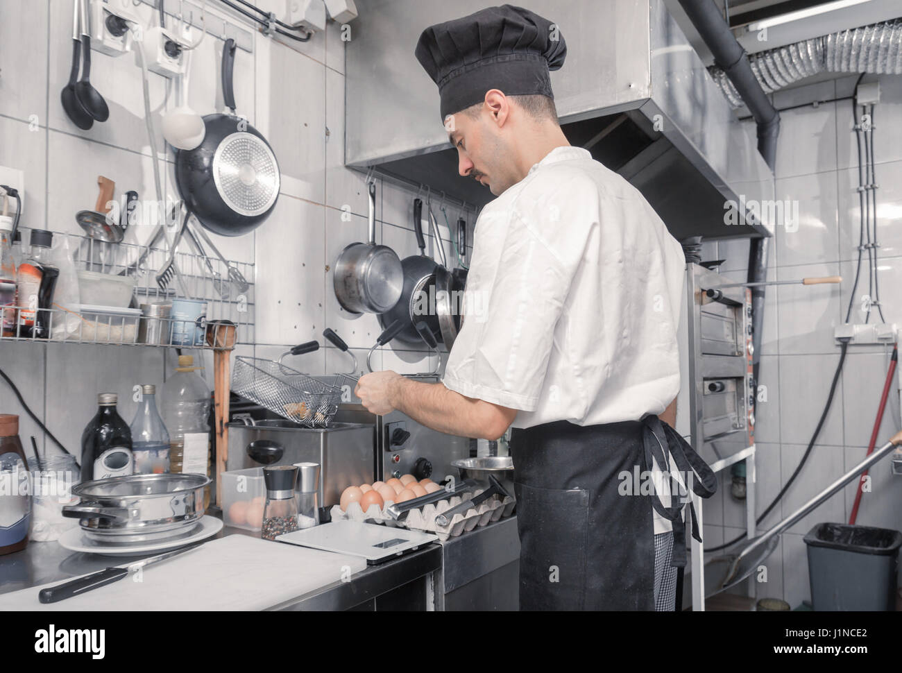 one young adult man chef using frying, deep fryer, professional commercial  kitchen Stock Photo - Alamy