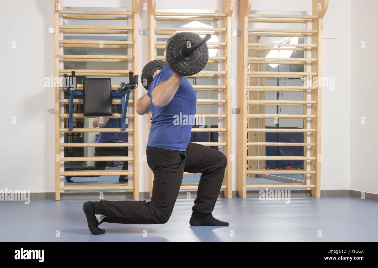 one young adult man only, muscular big bulky, weight bar, indoors, Single Leg Squat, one leg squat Stock Photo