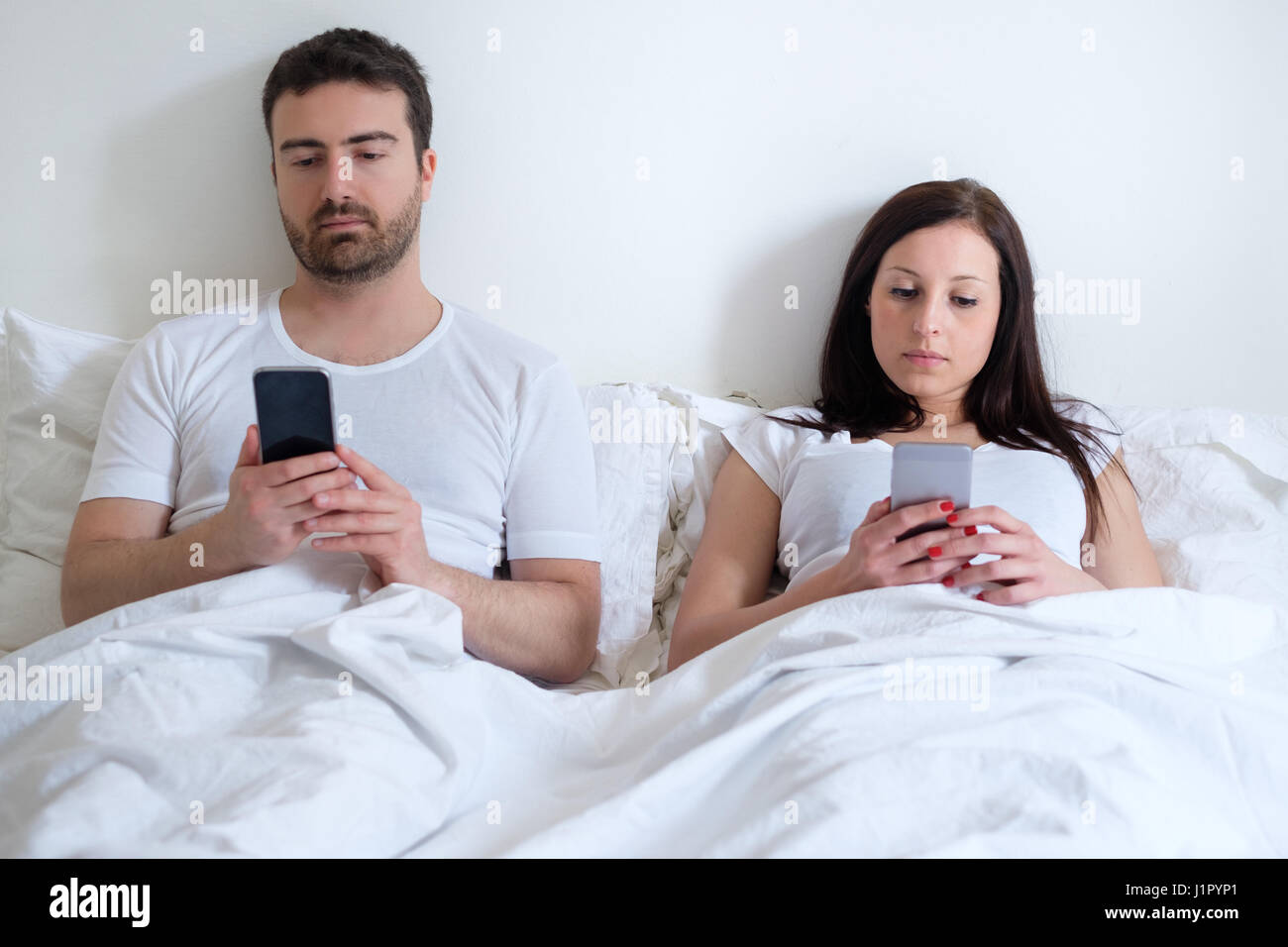 Bored and annoyed lovers couple ignoring themselves Stock Photo