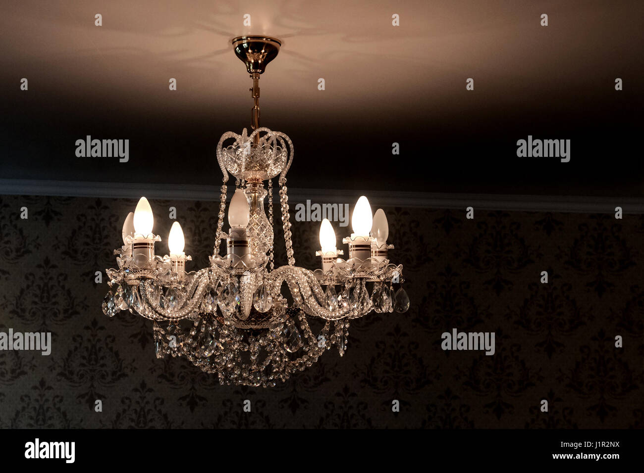crystal chandelier shines hanging from the ceiling in the room Stock Photo